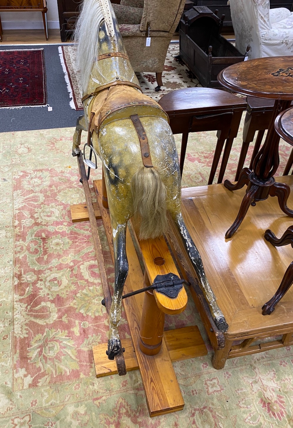 An early 20th century Ayers type dapple rocking horse with tan leather tack on pine safety frame, length 145cm, height 124cm